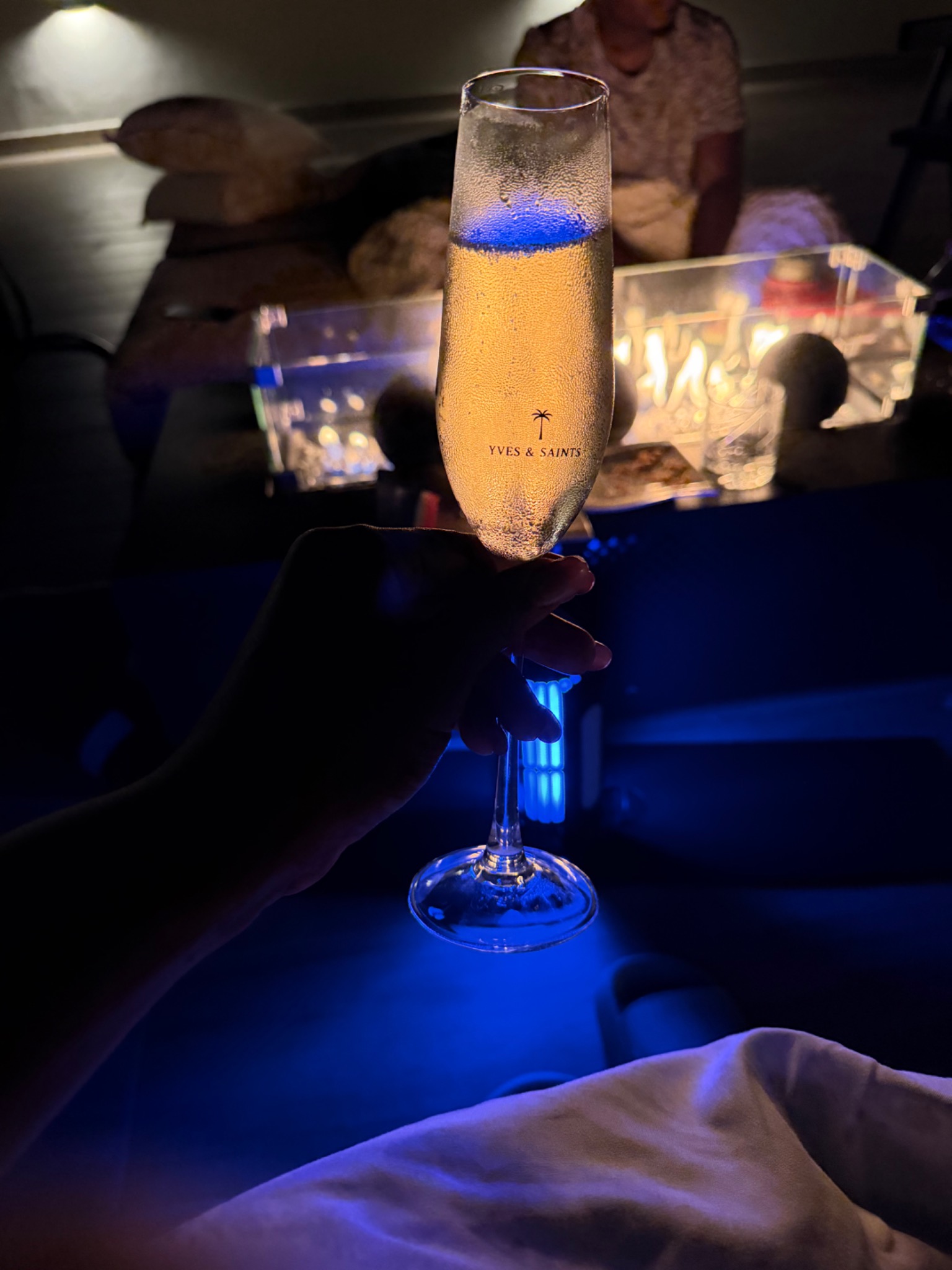 Yves & Saints champagne flute beside the fire after dark